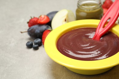 Photo of Healthy baby food in bowl on grey table, closeup