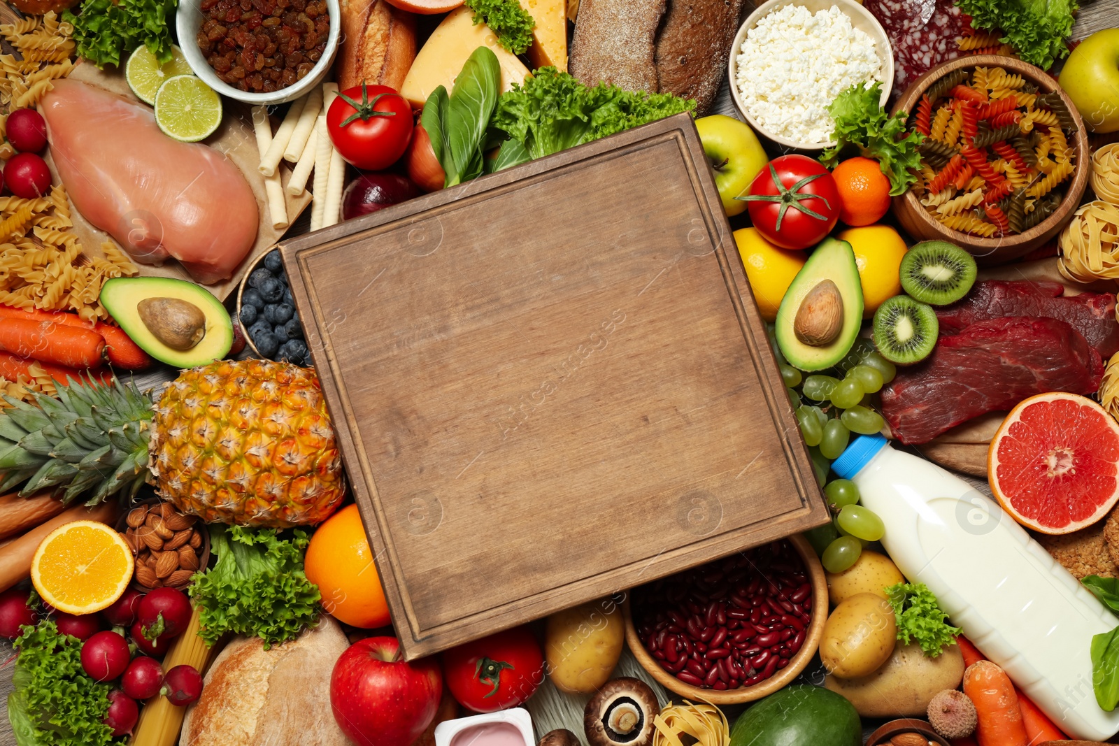 Photo of Wooden board on pile of different food products, top view with space for text. Healthy balanced diet