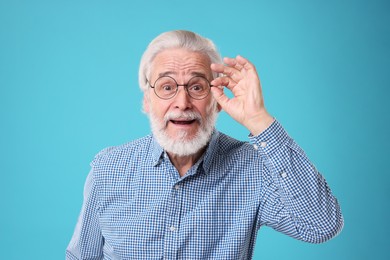 Photo of Portrait of stylish grandpa with glasses on light blue background