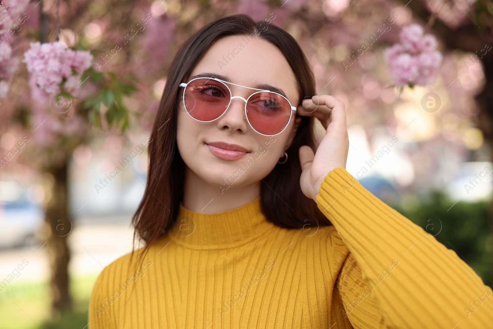 Photo of Beautiful woman in sunglasses near blossoming tree on spring day