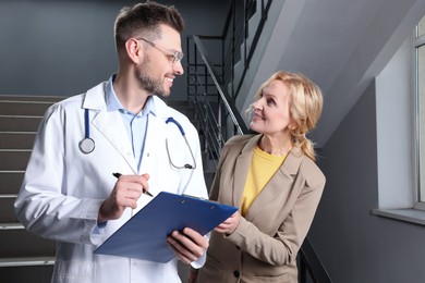 Photo of Happy doctor with clipboard and patient in clinic