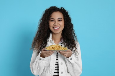 African American woman with French fries on light blue background
