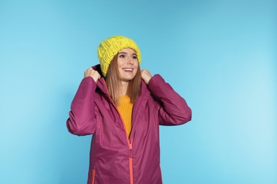 Young woman wearing warm clothes on color background. Ready for winter vacation