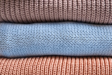 Photo of Stack of warm knitted clothes as background