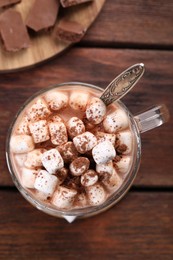 Photo of Cup of aromatic hot chocolate with marshmallows and cocoa powder on wooden table, top view