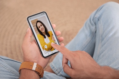 Man visiting dating site via smartphone indoors, closeup