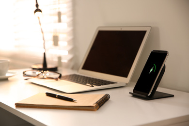 Photo of Stylish workplace with laptop, mobile phone and wireless charger
