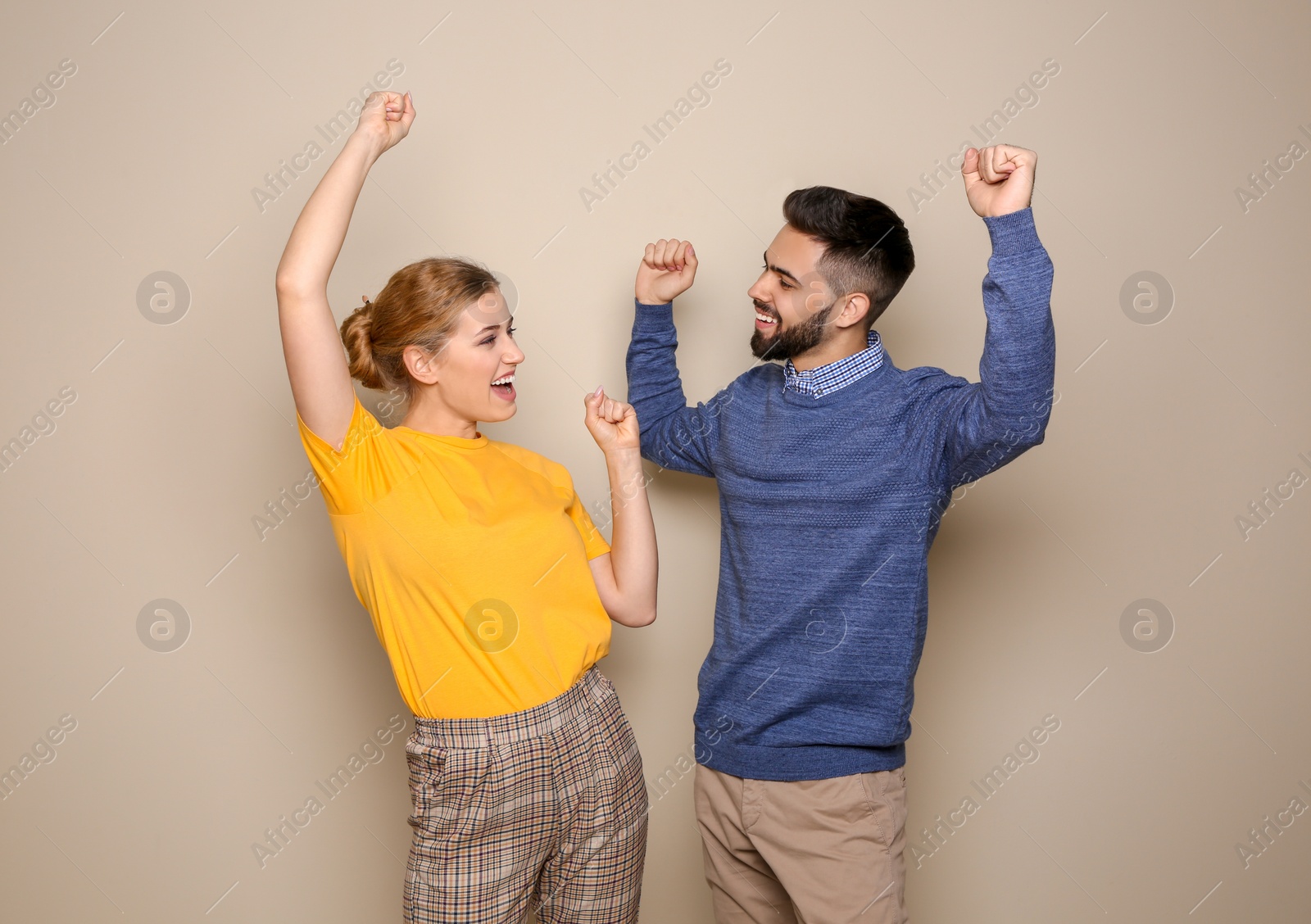 Photo of Happy young people celebrating victory on color background