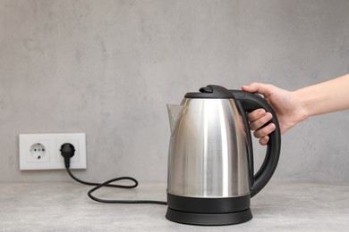 Photo of Woman with electric kettle in kitchen, closeup. Space for text