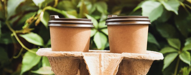 Image of Two takeaway paper coffee cups cardboard holder in outdoors. Banner design