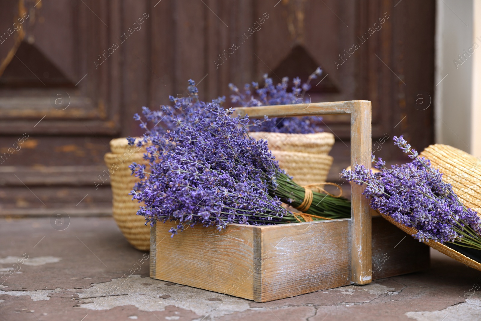 Photo of Beautiful lavender flowers and straw hat near building outdoors