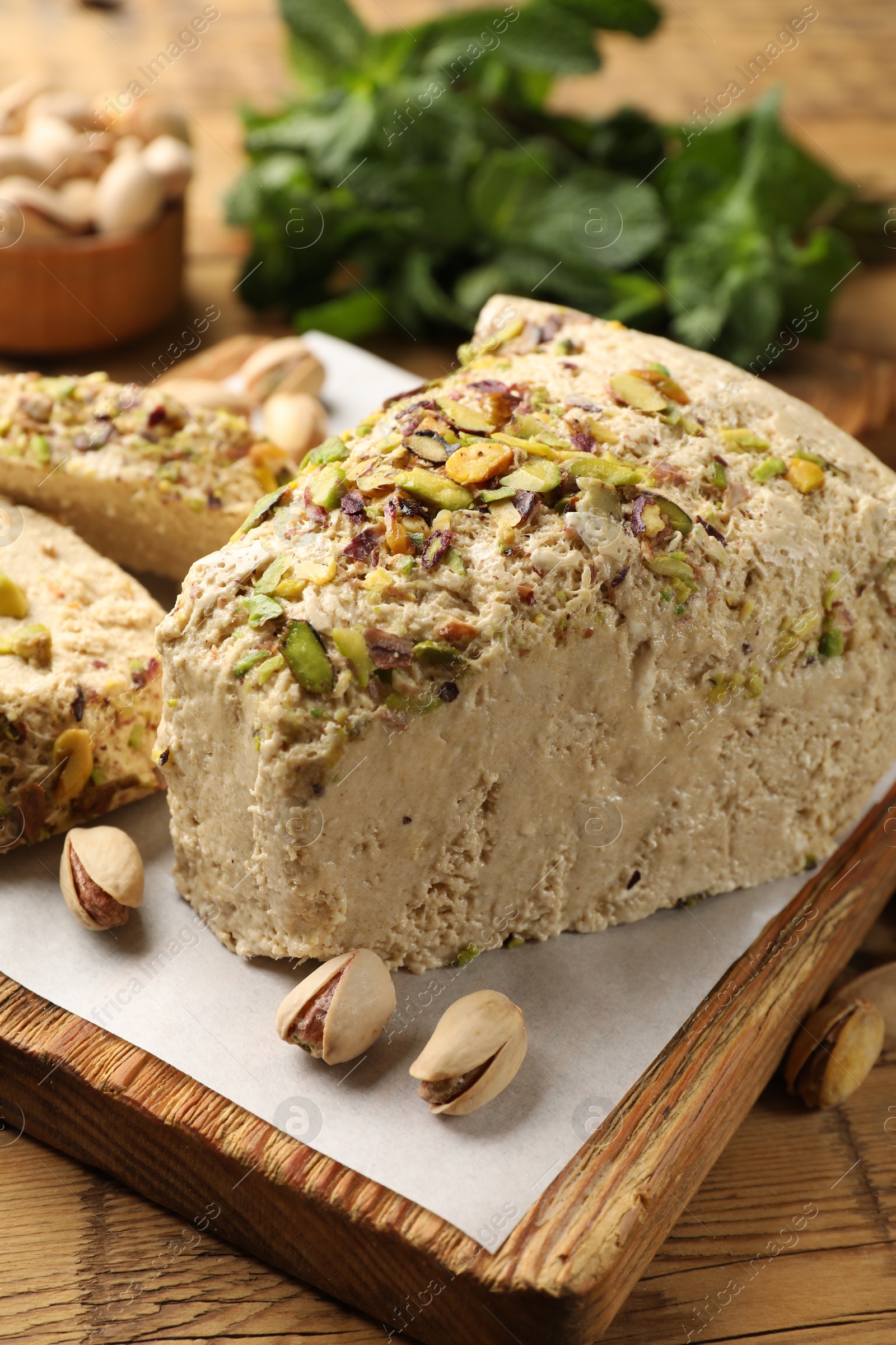 Photo of Tasty halva with pistachios and mint on table, closeup