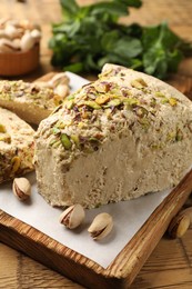 Photo of Tasty halva with pistachios and mint on table, closeup