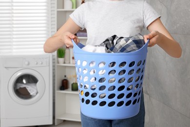 Photo of Woman with basket full of laundry in bathroom, closeup