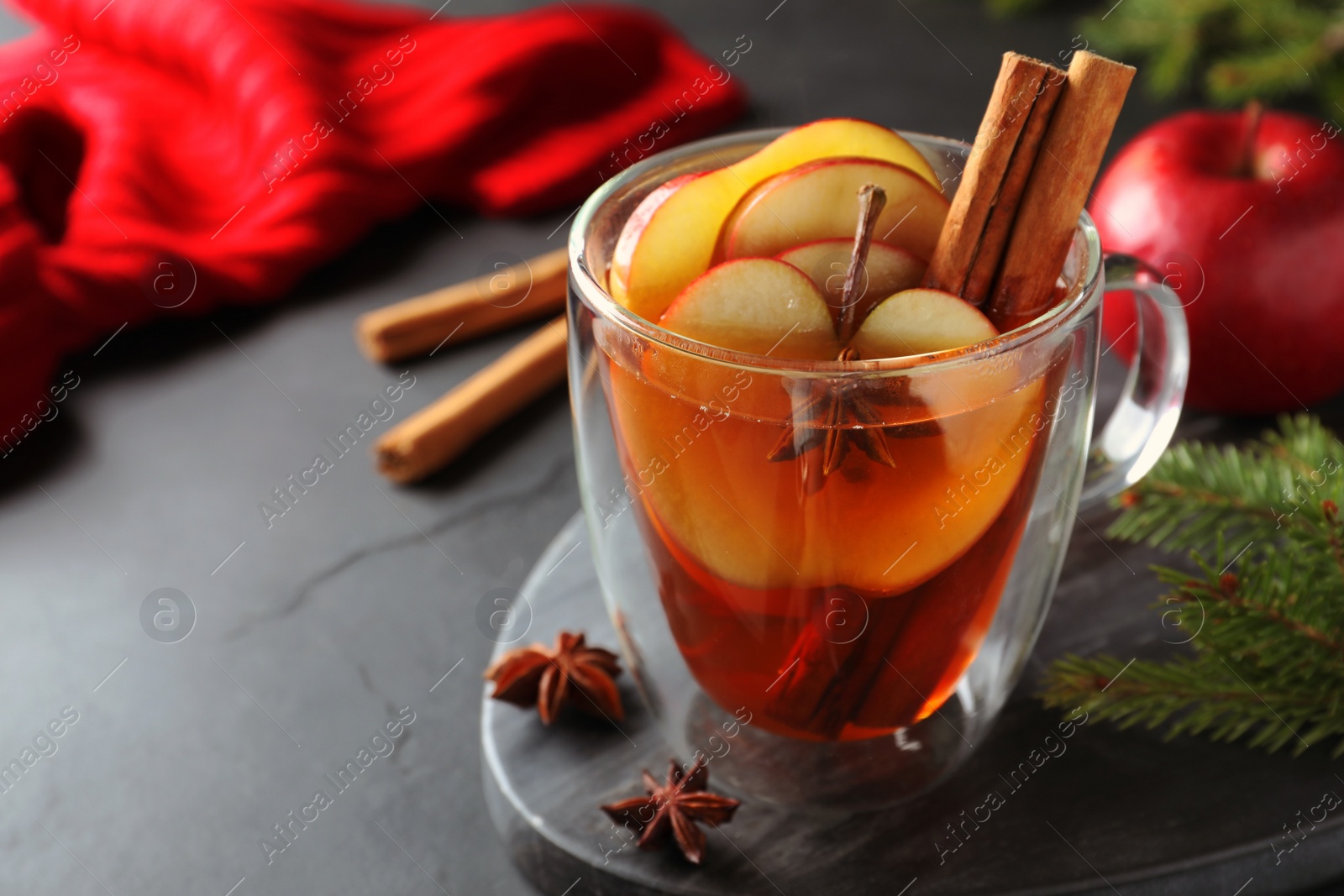 Photo of Aromatic hot mulled cider on black table. Space for text