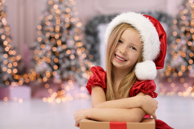 Photo of Cute little child with Christmas gift at home. Space for text