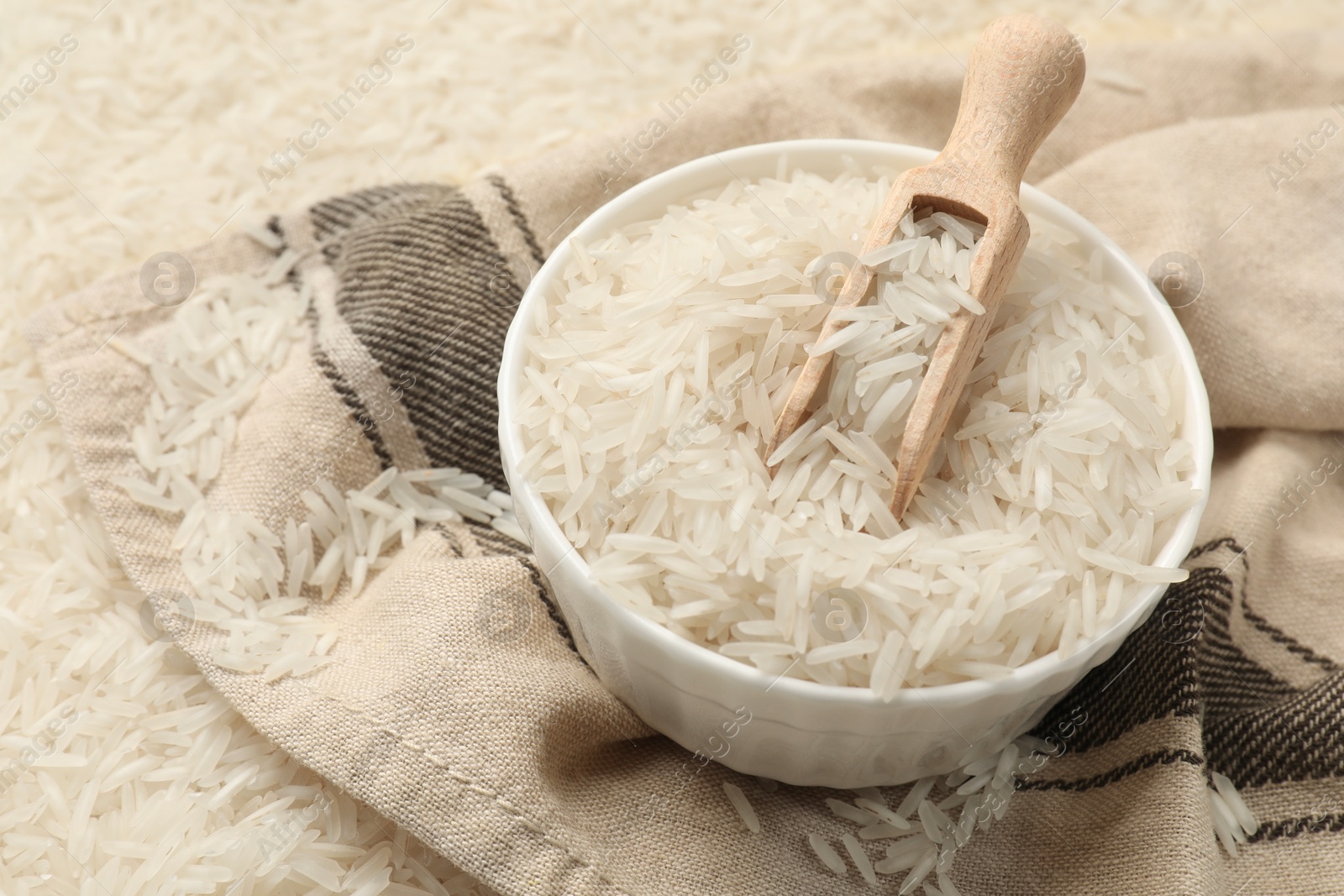 Photo of Raw basmati rice, bowl, scoop and cloth, closeup