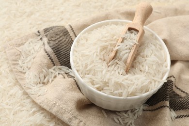 Photo of Raw basmati rice, bowl, scoop and cloth, closeup