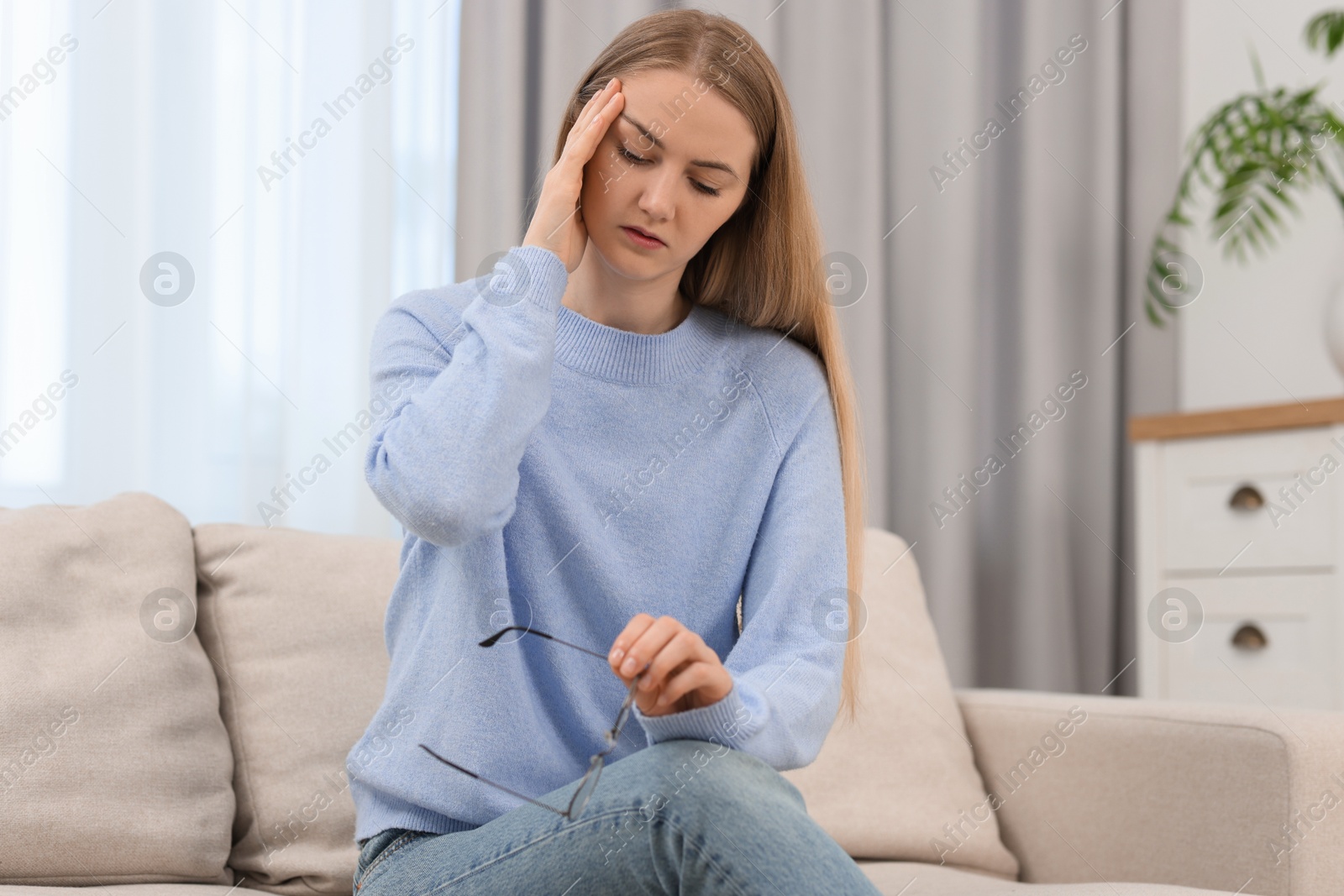 Photo of Overwhelmed young woman with glasses suffering from headache at home