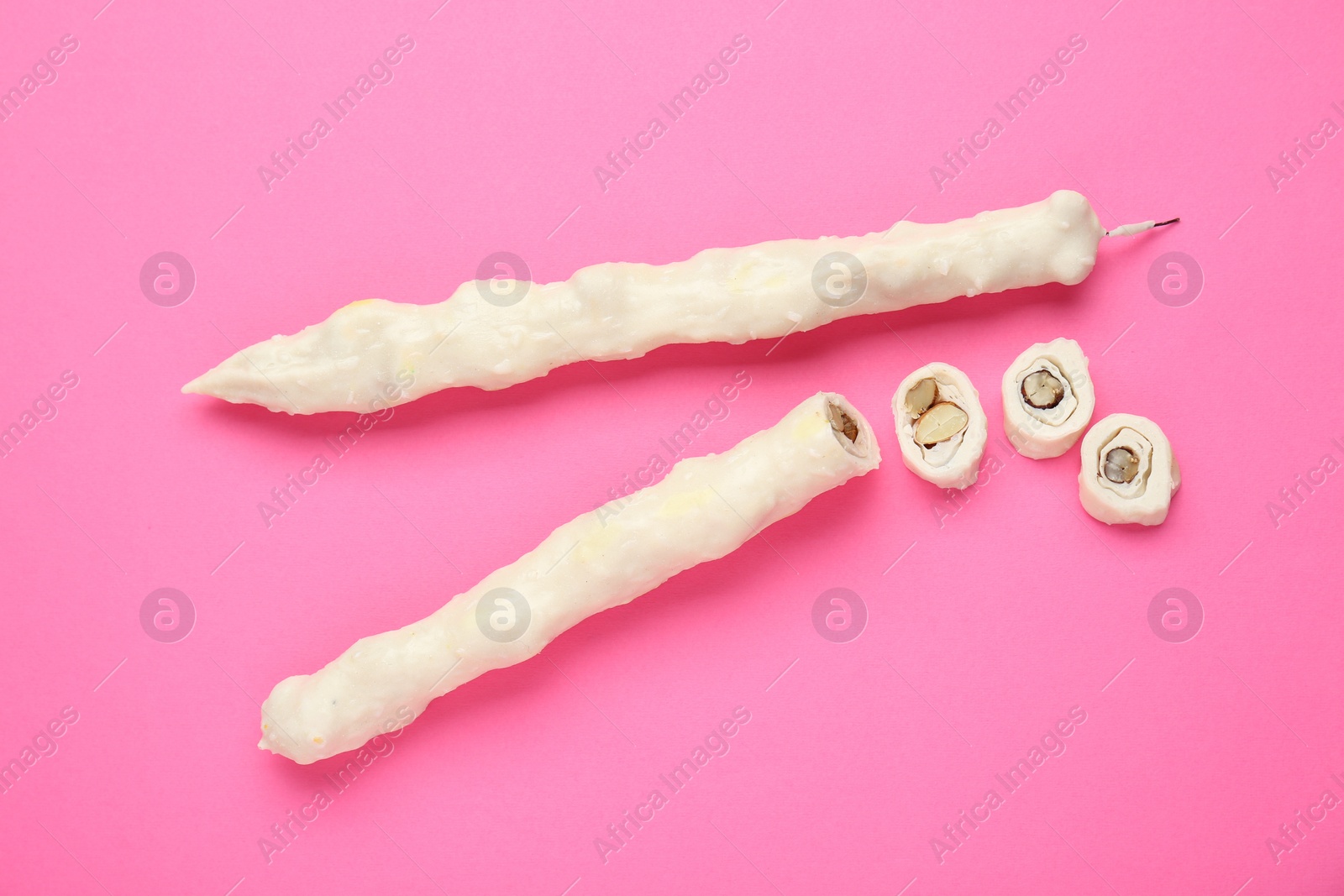 Photo of Delicious churchkhelas on pink background, flat lay