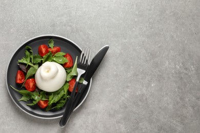 Photo of Delicious burrata salad with tomatoes and arugula served on grey table, top view. Space for text