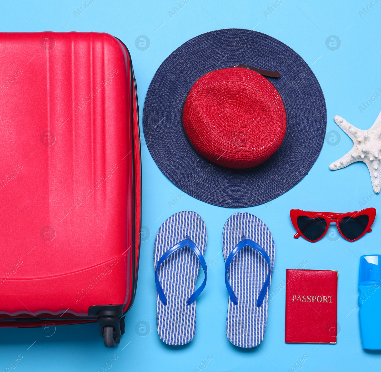 Photo of Blue suitcase and beach objects on blue background, flat lay