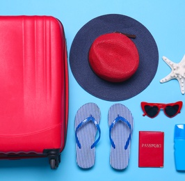 Photo of Blue suitcase and beach objects on blue background, flat lay