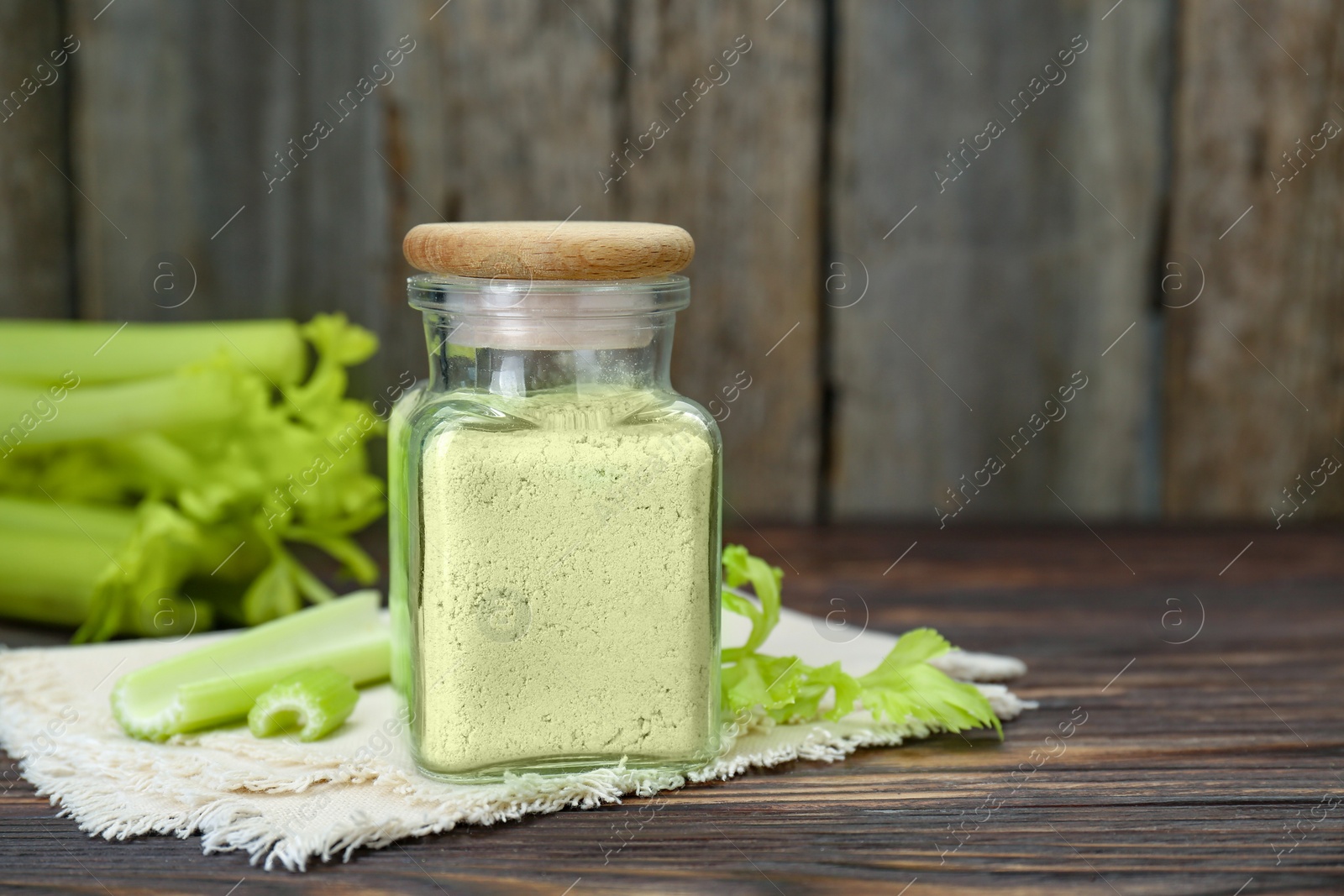 Photo of Natural celery powder in jar and fresh stalks on wooden table, space for text