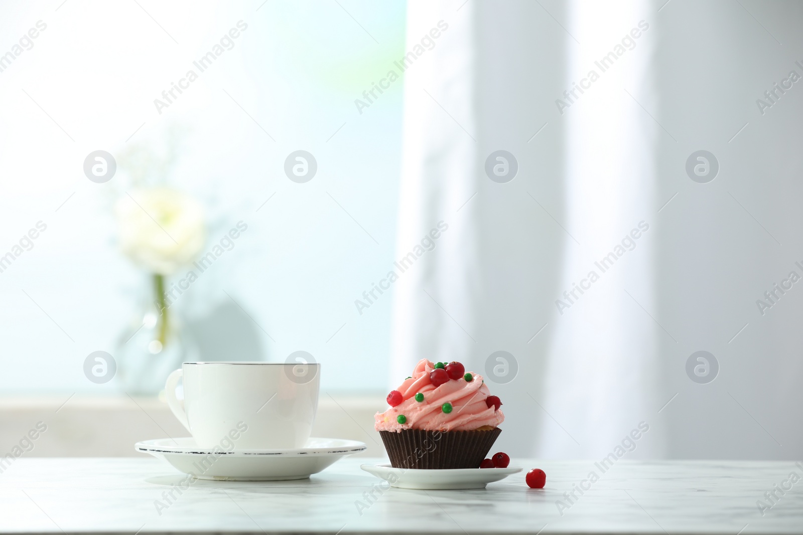 Photo of Delicious cupcake with pink cream and tea on white table