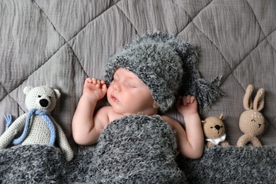 Photo of Cute newborn baby sleeping with toys in bed, top view