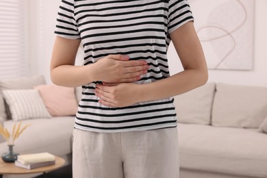 Young woman suffering from stomach pain at home, closeup