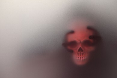 Photo of Silhouette of creepy ghost with skull behind cloth, space for text. Color toned
