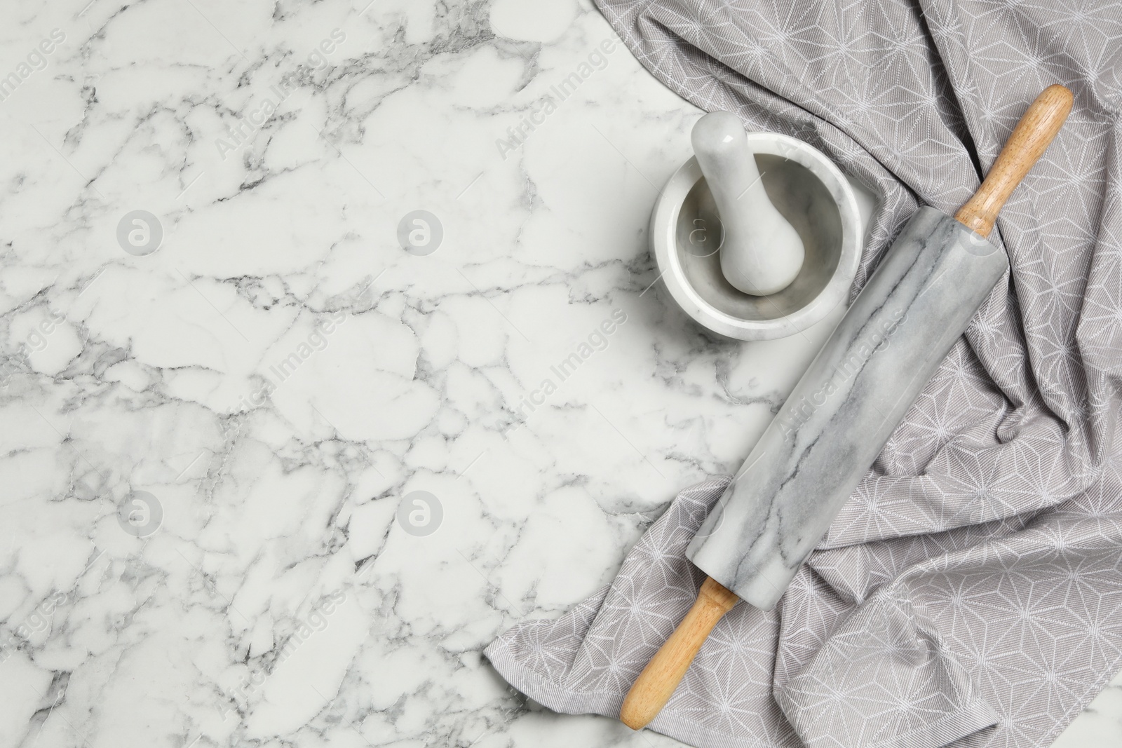 Photo of Rolling pin, mortar and pestle on white marble table, flat lay with space for text. Cooking utensils