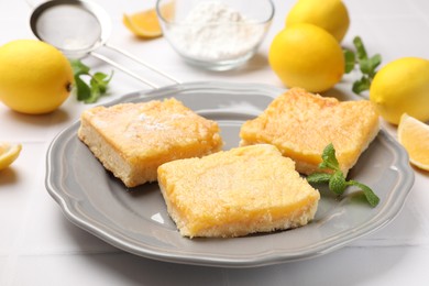 Photo of Tasty lemon bars and mint on white table, closeup