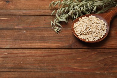 Photo of Spoon with oatmeal and floret branches on wooden table. Space for text