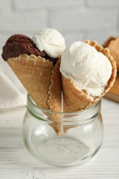 Ice cream scoops in wafer cones on white wooden table