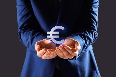 Man demonstrating virtual euro sign on grey background, closeup