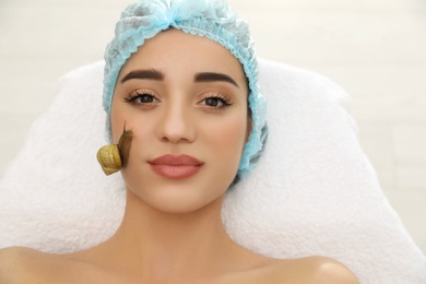 Photo of Young woman receiving snail facial massage in spa salon