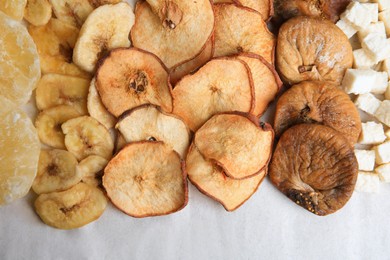 Different tasty dried fruits on paper, flat lay