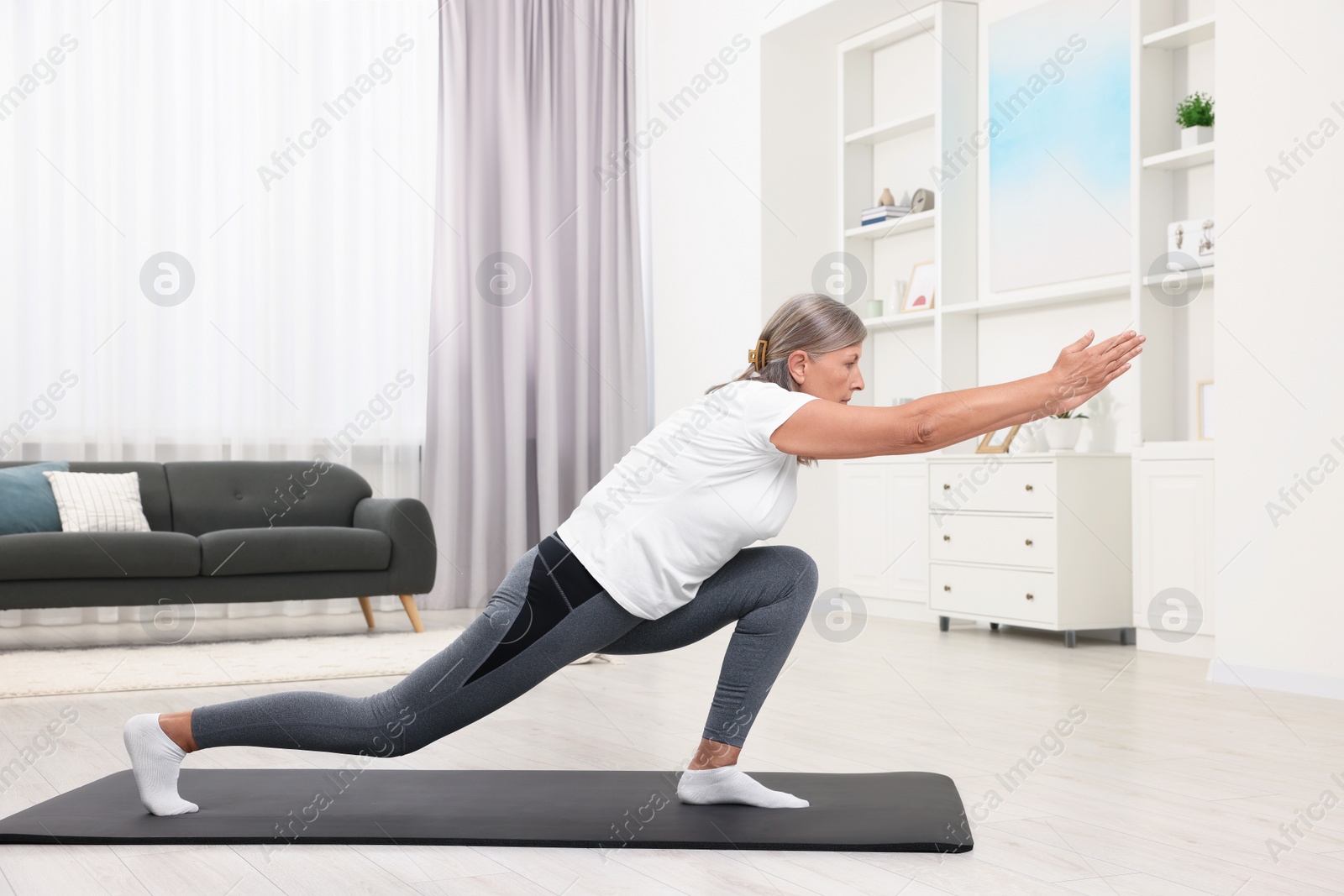 Photo of Senior woman practicing yoga on mat at home