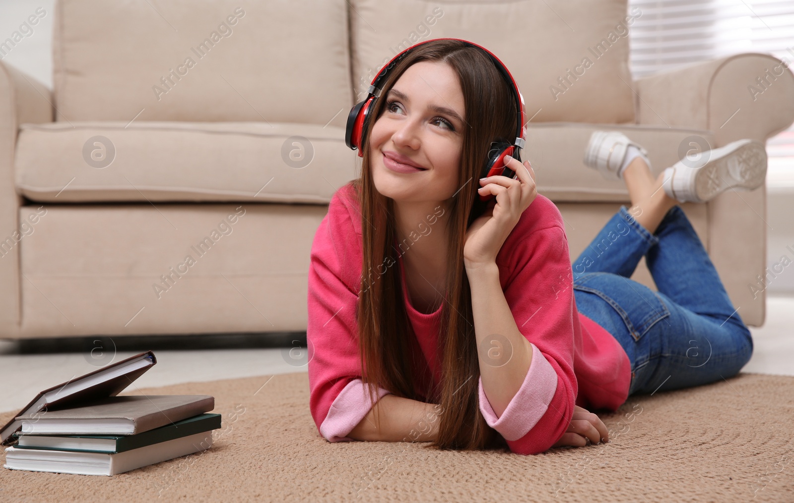 Photo of Woman listening to audiobook lying on floor at home
