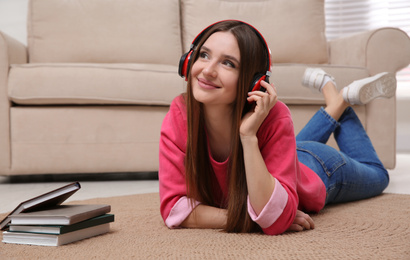 Photo of Woman listening to audiobook lying on floor at home
