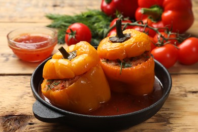 Photo of Tasty stuffed peppers in pan on wooden table, closeup