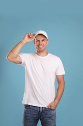 Photo of Happy man in white cap and tshirt on light blue background. Mockup for design