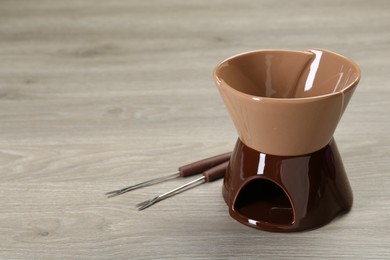 Fondue set on wooden table, space for text