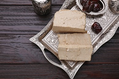 Pieces of tasty halva served on vintage tray on wooden table, above view. Space for text