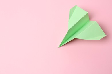 Photo of Green paper plane on pink background, top view. Space for text