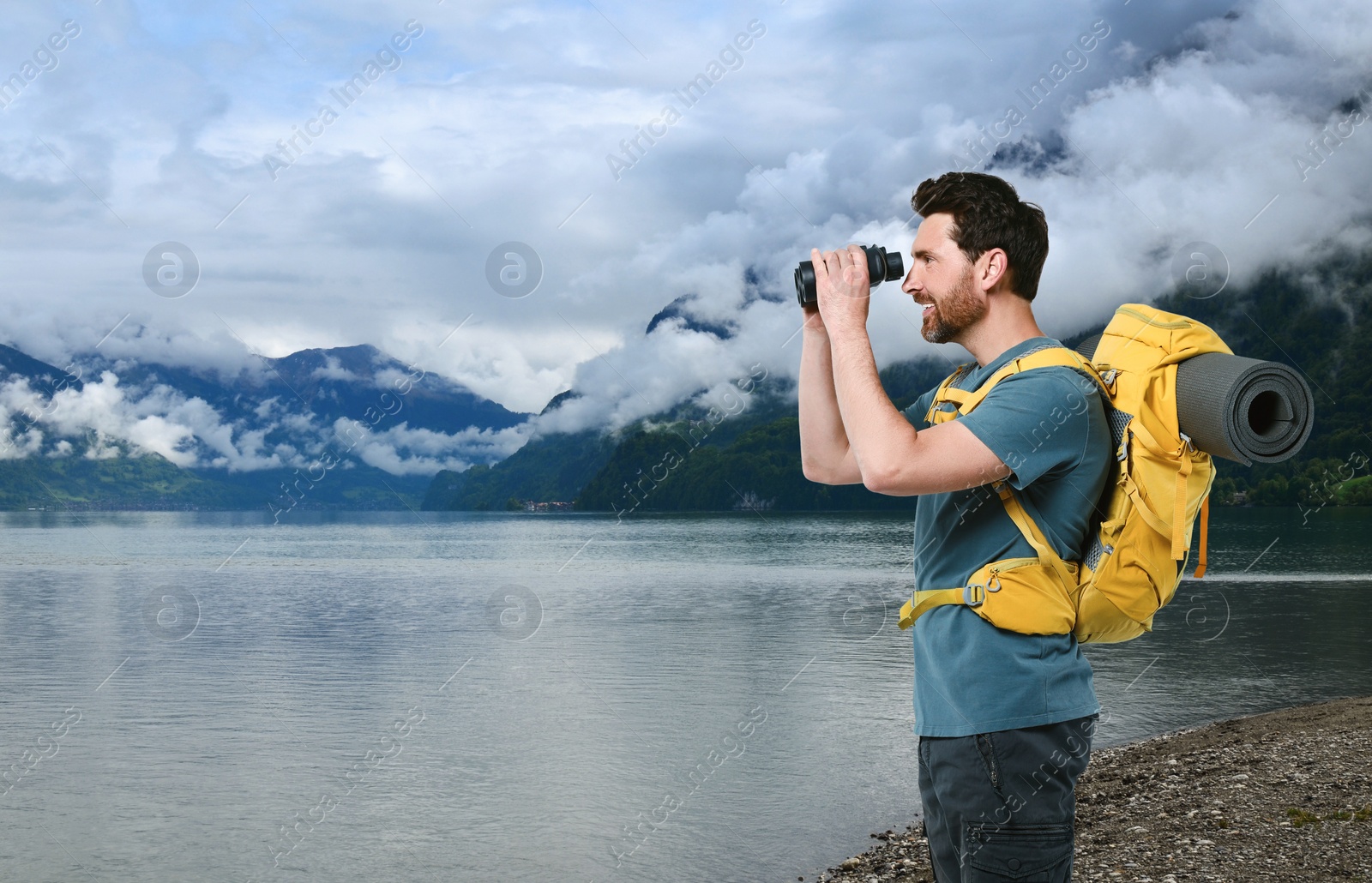 Image of Happy tourist with backpack and binoculars near lake