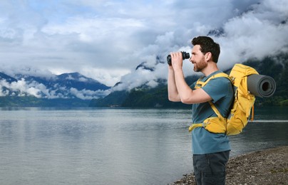 Image of Happy tourist with backpack and binoculars near lake