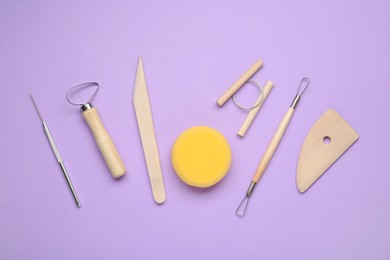 Set of clay modeling tools on violet background, flat lay